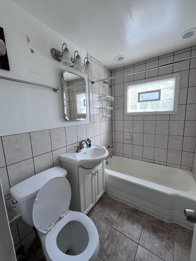 full bathroom featuring toilet, tile walls, vanity, tiled shower / bath combo, and tile patterned flooring