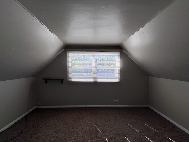 bonus room with lofted ceiling and dark colored carpet