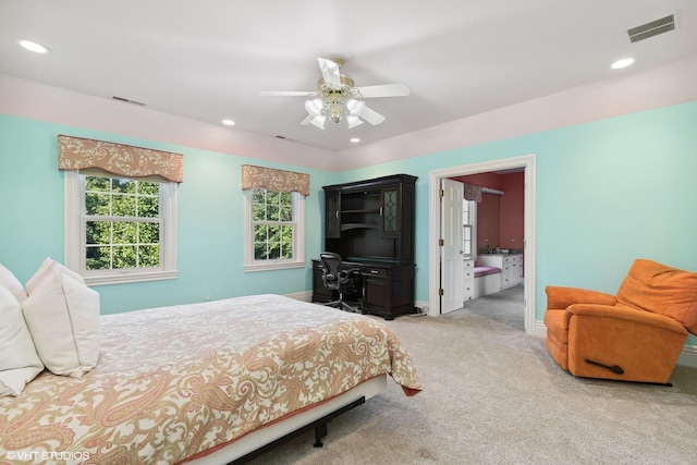 bedroom with light carpet, ensuite bath, and ceiling fan