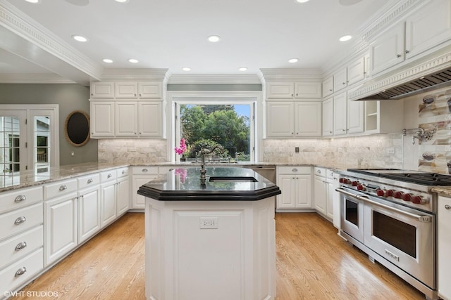 kitchen featuring sink, extractor fan, double oven range, a kitchen island, and white cabinets