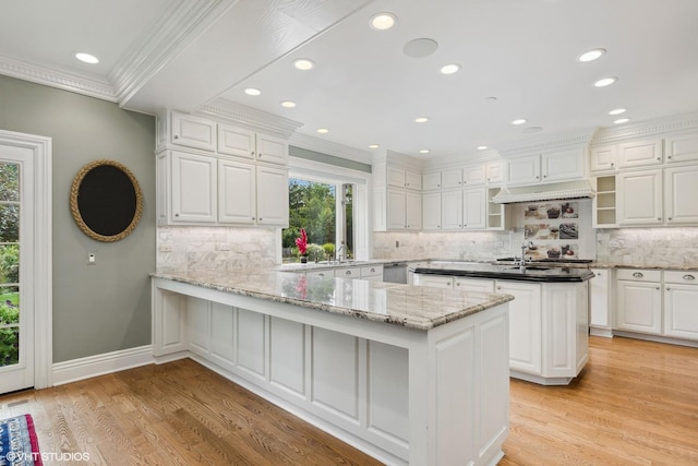 kitchen with sink, white cabinets, light wood-type flooring, and kitchen peninsula