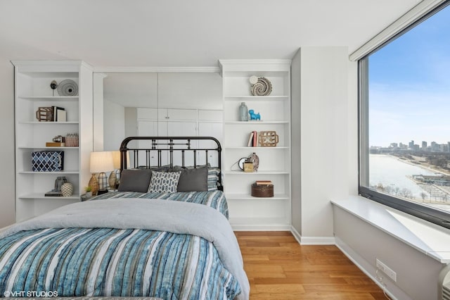 bedroom featuring a water view and light hardwood / wood-style floors