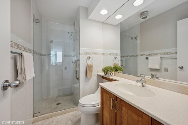 bathroom with walk in shower, toilet, tile walls, vanity, and tile patterned flooring