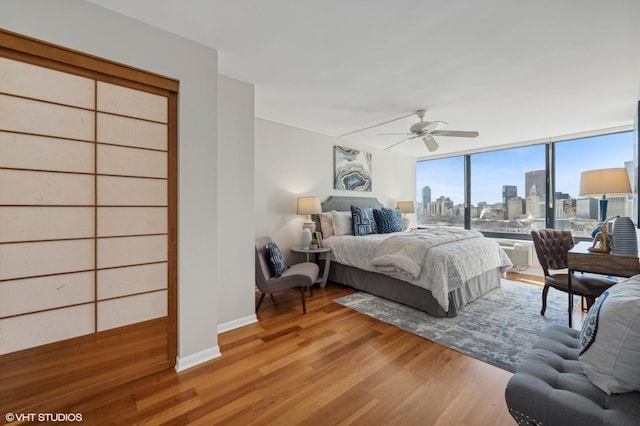 bedroom with ceiling fan, hardwood / wood-style floors, and a wall of windows