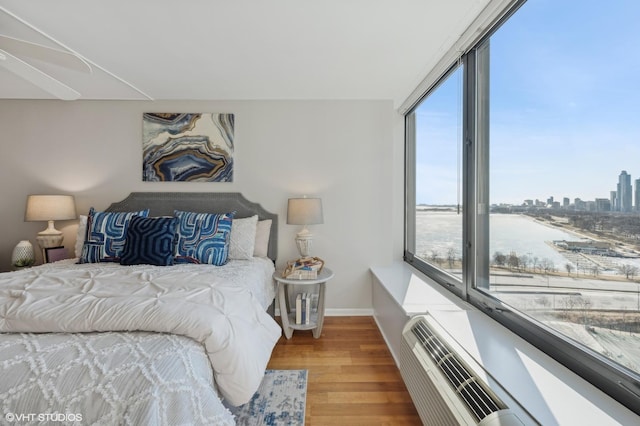 bedroom featuring multiple windows, hardwood / wood-style floors, and a water view