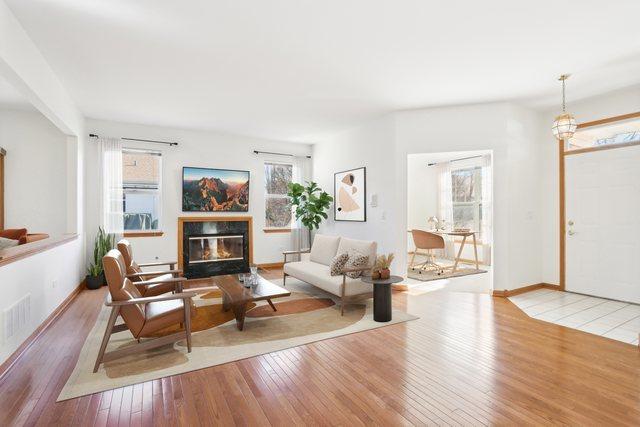 living area featuring visible vents, wood-type flooring, baseboards, and a glass covered fireplace