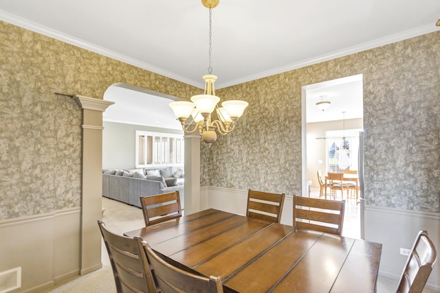 unfurnished dining area featuring an inviting chandelier, carpet floors, crown molding, and decorative columns