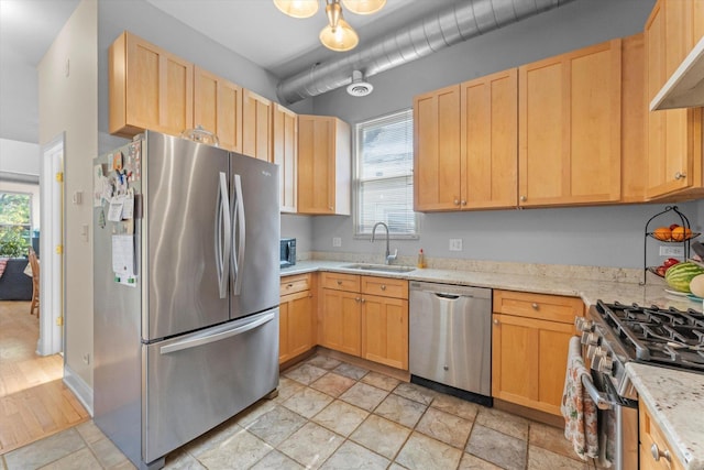 kitchen featuring light brown cabinetry, sink, stainless steel appliances, and light stone countertops