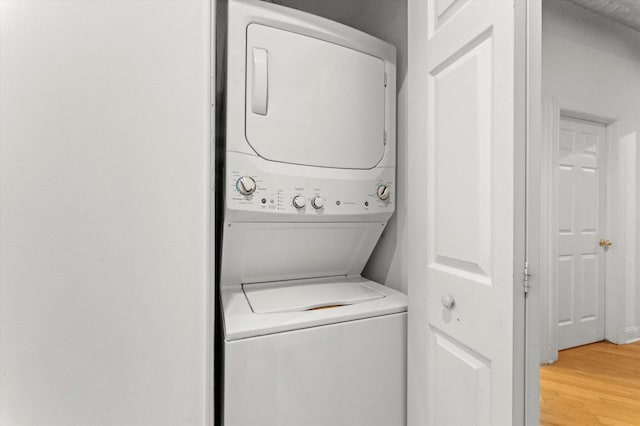 washroom with hardwood / wood-style floors and stacked washer and clothes dryer