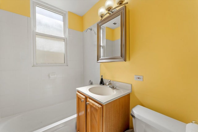 full bathroom featuring vanity, tiled shower / bath combo, and toilet