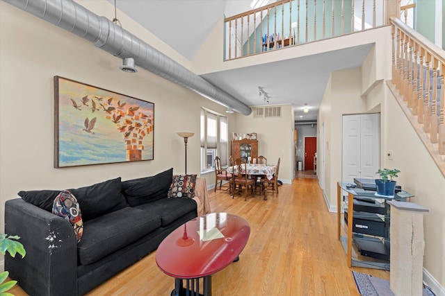 living room featuring a towering ceiling and light hardwood / wood-style flooring