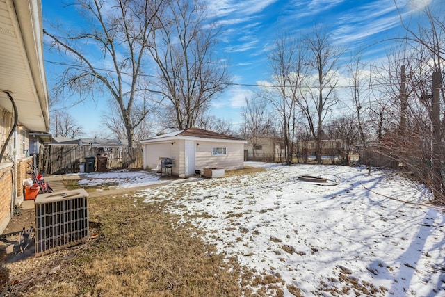 yard covered in snow featuring cooling unit, a garage, and an outbuilding