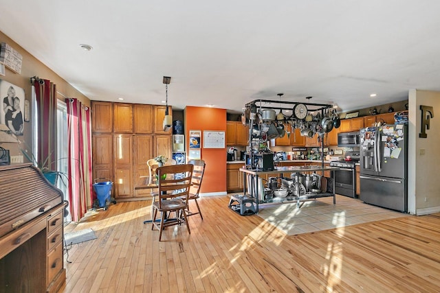 kitchen featuring stainless steel appliances, pendant lighting, and light hardwood / wood-style floors