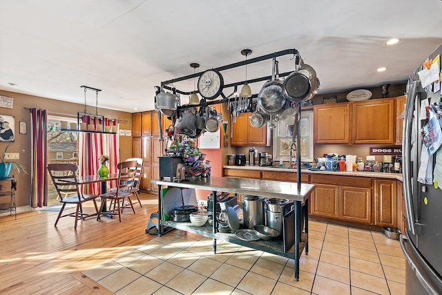 kitchen with pendant lighting, stainless steel refrigerator, sink, and light tile patterned floors