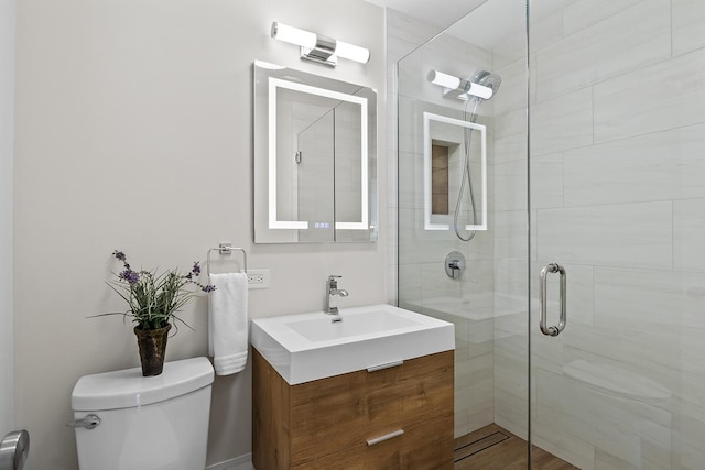 bathroom with toilet, vanity, and a shower with shower door