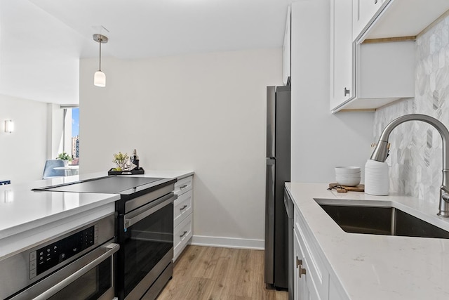 kitchen featuring pendant lighting, sink, stainless steel appliances, and white cabinets