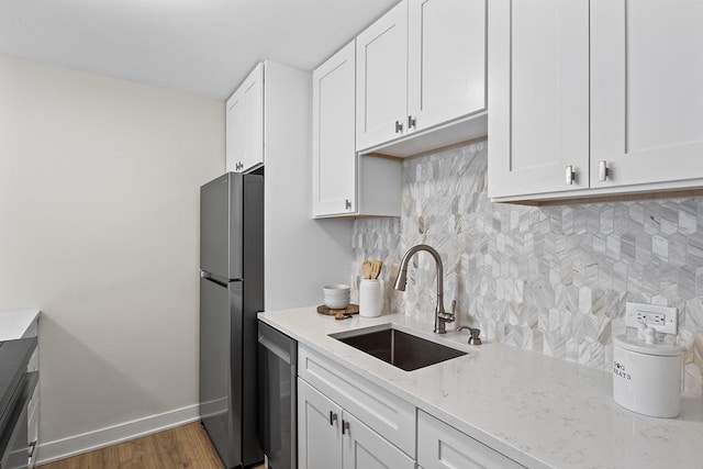 kitchen with sink, appliances with stainless steel finishes, tasteful backsplash, light stone countertops, and white cabinets