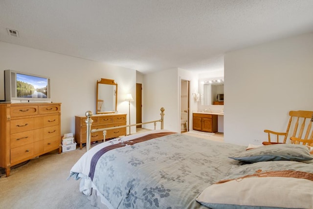 bedroom featuring light carpet, a textured ceiling, and ensuite bathroom