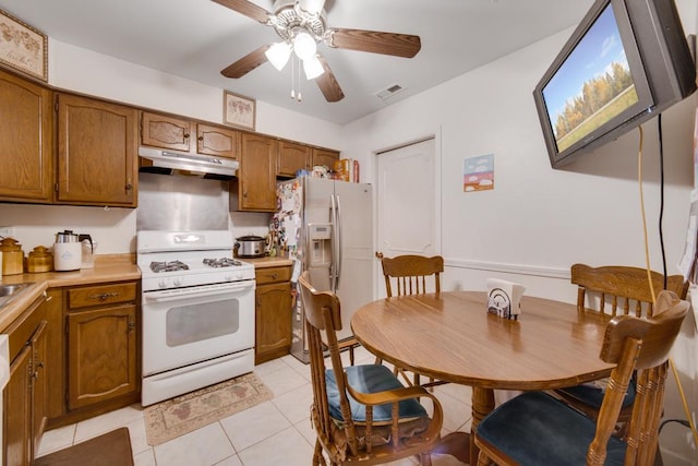 kitchen featuring white range with gas cooktop, light tile patterned floors, stainless steel fridge, and ceiling fan