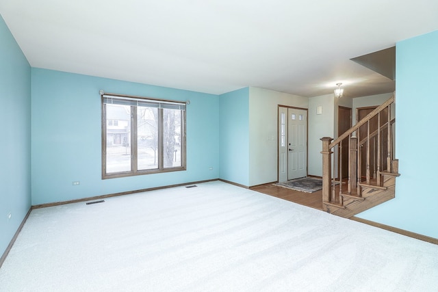 spare room with baseboards, visible vents, stairway, and carpet flooring