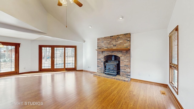 unfurnished living room featuring ceiling fan, high vaulted ceiling, light hardwood / wood-style floors, french doors, and a wood stove