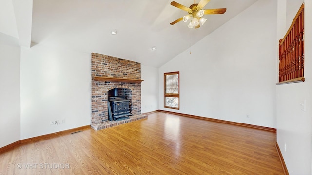 unfurnished living room with hardwood / wood-style flooring, high vaulted ceiling, ceiling fan, and a wood stove