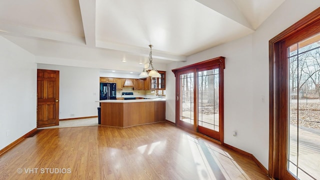 kitchen with black refrigerator, decorative light fixtures, a wealth of natural light, and kitchen peninsula