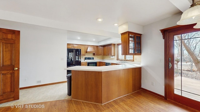 kitchen with kitchen peninsula, light hardwood / wood-style floors, custom range hood, and black appliances