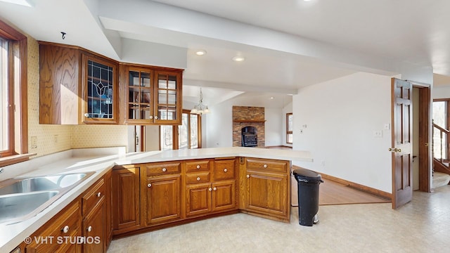 kitchen with lofted ceiling, sink, hanging light fixtures, a brick fireplace, and kitchen peninsula