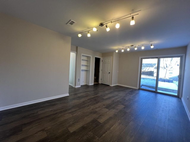 spare room featuring dark wood-type flooring and built in shelves