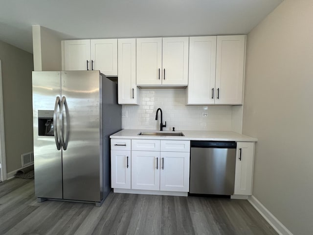 kitchen with sink, dark wood-type flooring, stainless steel appliances, white cabinets, and decorative backsplash