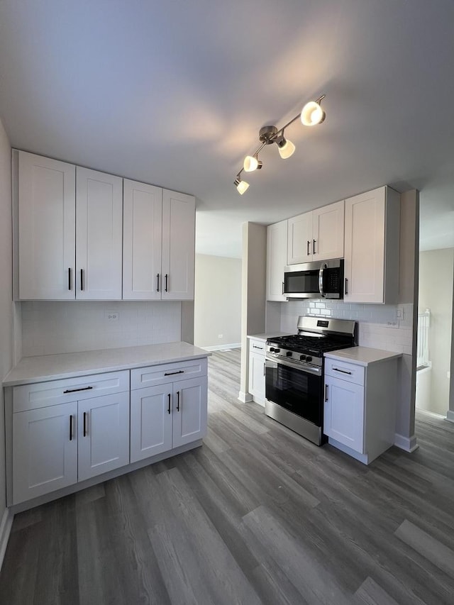 kitchen with tasteful backsplash, appliances with stainless steel finishes, dark hardwood / wood-style floors, and white cabinets