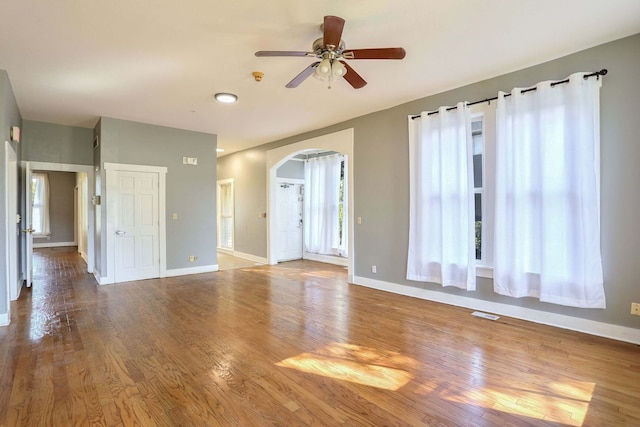 empty room featuring ceiling fan, plenty of natural light, and hardwood / wood-style floors