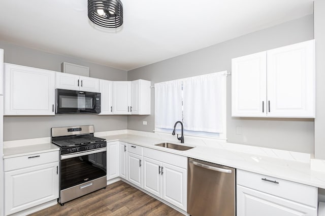 kitchen featuring sink, dark wood-type flooring, appliances with stainless steel finishes, light stone counters, and white cabinets