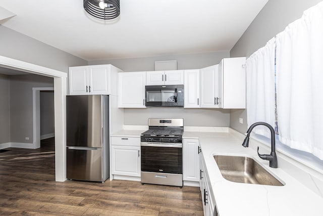 kitchen with appliances with stainless steel finishes, sink, white cabinets, and dark hardwood / wood-style flooring