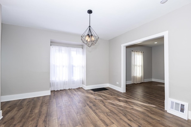 unfurnished room featuring dark hardwood / wood-style flooring, a wealth of natural light, and an inviting chandelier