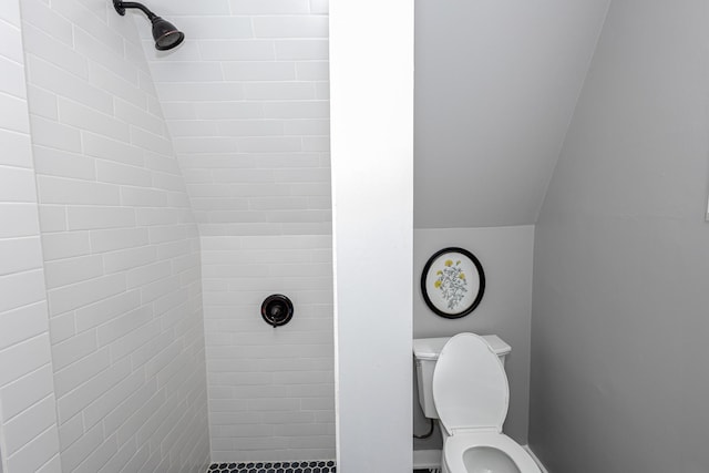 bathroom with a tile shower and toilet