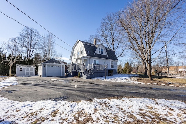 view of front facade with a wooden deck, a storage shed, and a garage