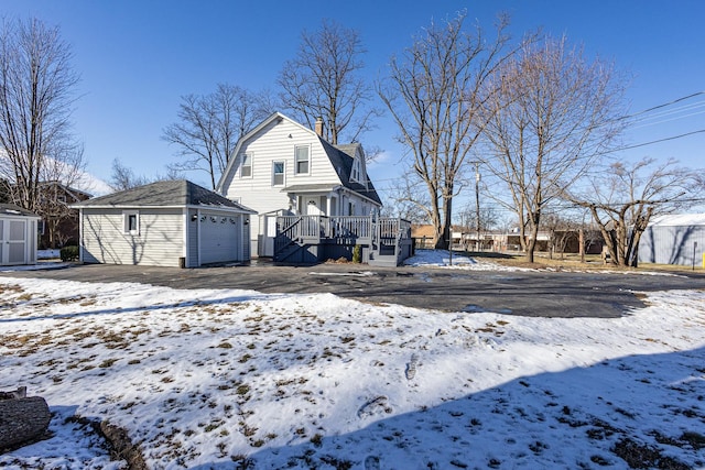 snow covered property featuring a garage and an outbuilding