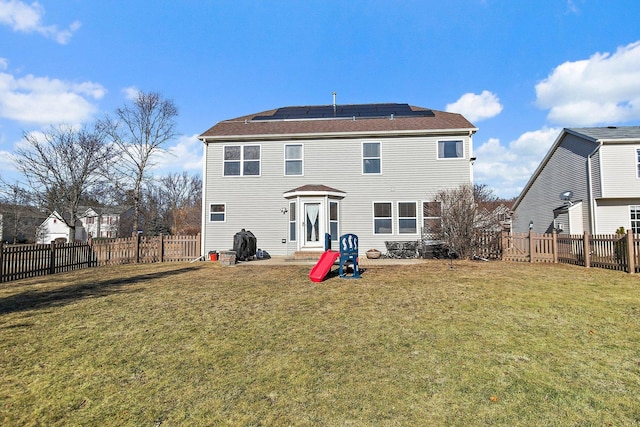 back of property featuring a lawn and solar panels