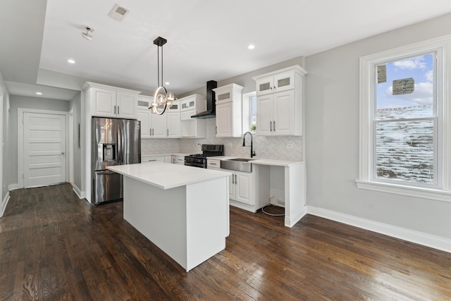 kitchen with a kitchen island, white cabinetry, stainless steel fridge with ice dispenser, gas range oven, and wall chimney exhaust hood