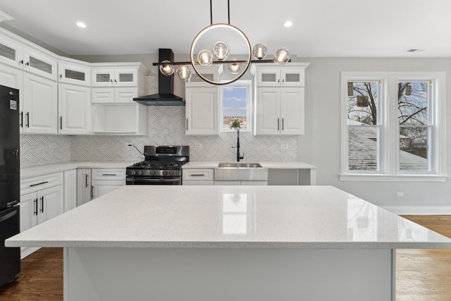 kitchen featuring white cabinetry, sink, gas stove, and wall chimney range hood