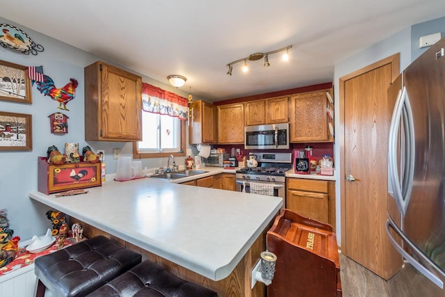 kitchen with appliances with stainless steel finishes, a breakfast bar, sink, and kitchen peninsula