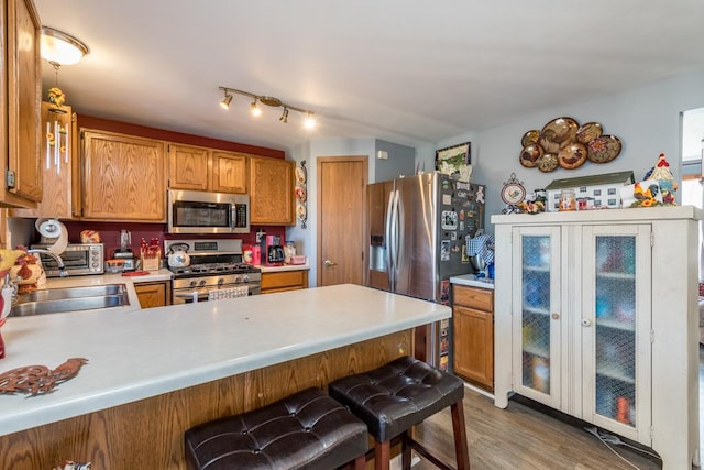 kitchen featuring a breakfast bar, sink, hardwood / wood-style flooring, kitchen peninsula, and stainless steel appliances