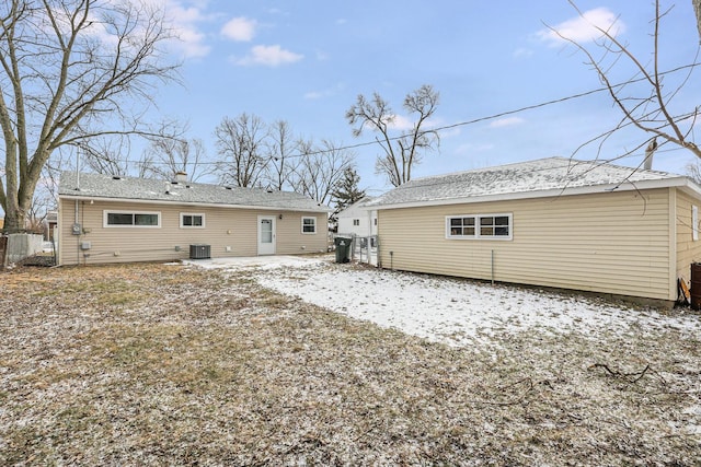 snow covered rear of property featuring central AC