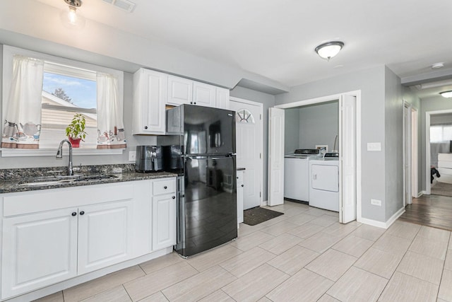 kitchen with black refrigerator, white cabinetry, sink, dark stone countertops, and washing machine and clothes dryer