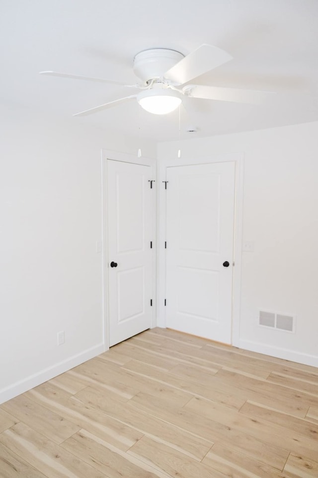 empty room with ceiling fan and light hardwood / wood-style flooring