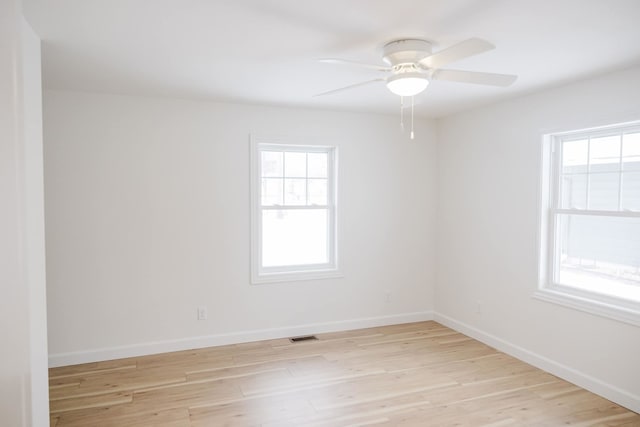 empty room featuring plenty of natural light, ceiling fan, and light wood-type flooring