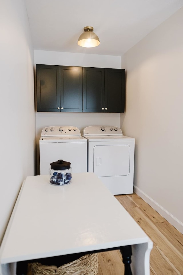 laundry room with separate washer and dryer, light hardwood / wood-style flooring, and cabinets