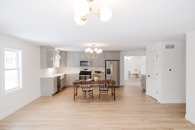 dining room featuring a notable chandelier, light hardwood / wood-style floors, and sink